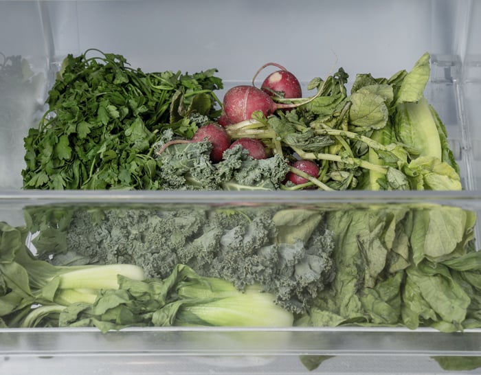 A fridge crisper drawer with wilted vegetables inside.