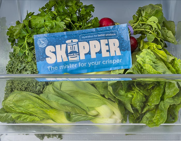 A crisper drawer with a Skipper pack and fresh, crisp vegetables inside.