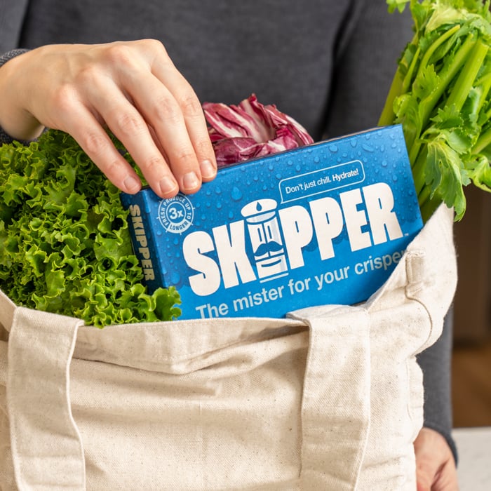 Hand removing a Skipper from a tote bag full of groceries.