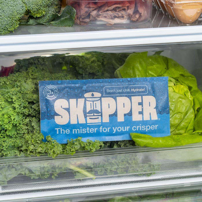 A skipper pack sitting with fresh crisp vegetables in a crisper drawer.